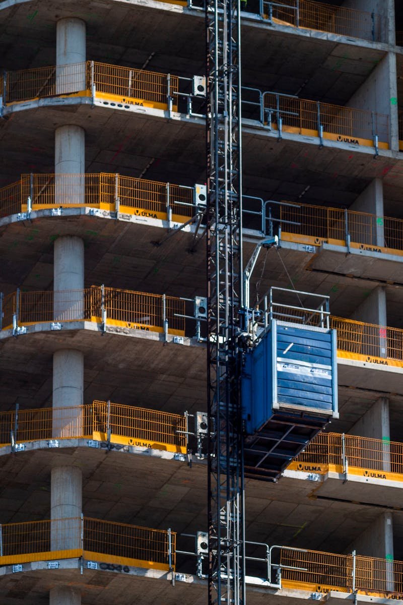 About Detailed view of a high-rise building construction featuring a crane and multi-level scaffolding.