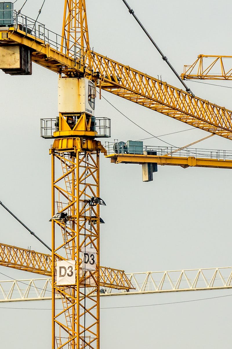 Cluster of yellow tower cranes at a construction site with a gloomy sky background.